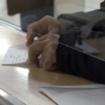 Osoba potpisuje dokument na šalteru za podnošenje zahteva za porodičnu penziju.
