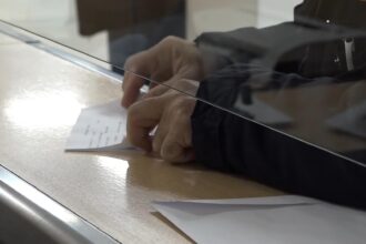Osoba potpisuje dokument na šalteru za podnošenje zahteva za porodičnu penziju.