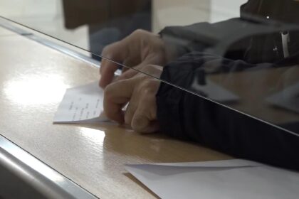 Osoba potpisuje dokument na šalteru za podnošenje zahteva za porodičnu penziju.
