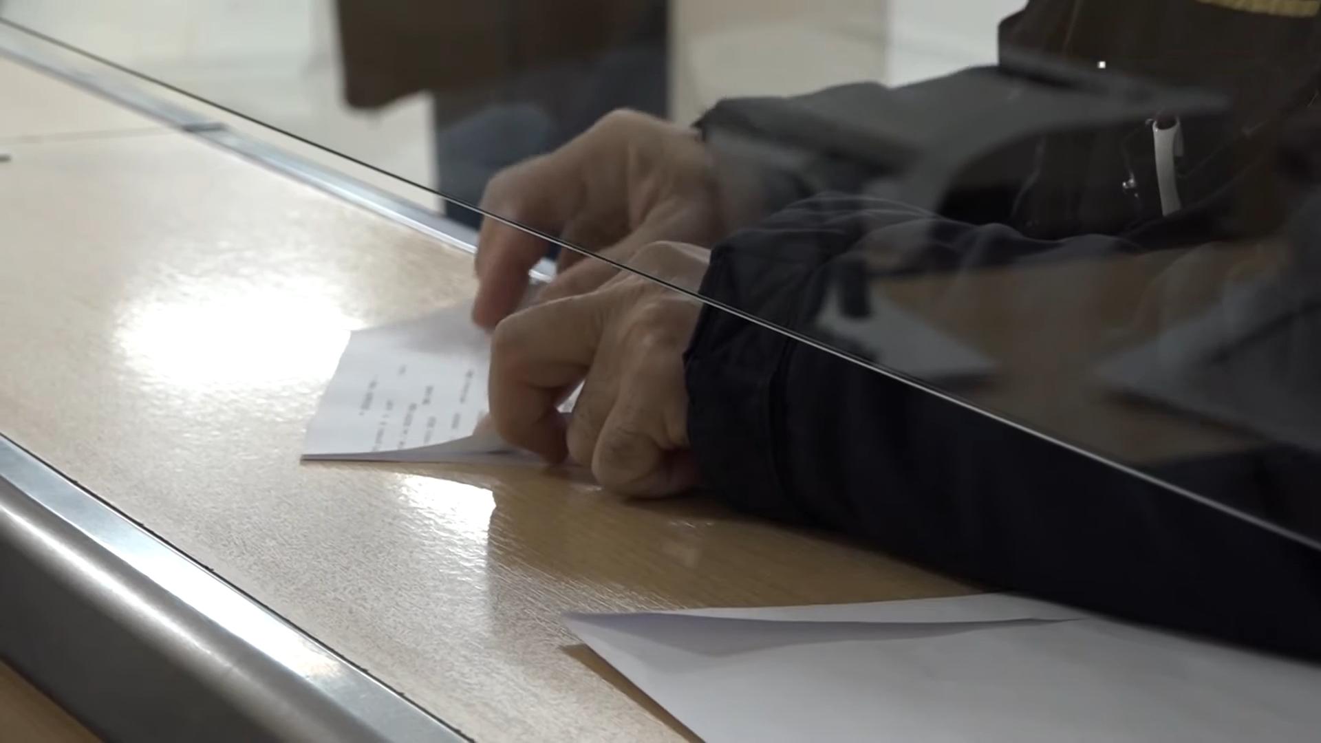 Osoba potpisuje dokument na šalteru za podnošenje zahteva za porodičnu penziju.